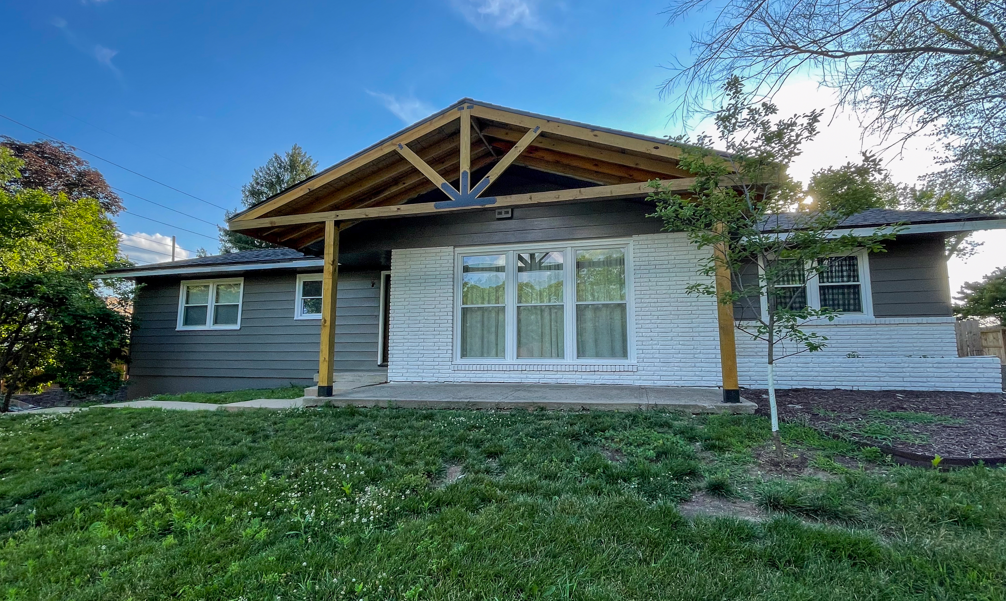 Modern gray ranch house exterior with natural timber front porch in Kansas City, MO by Red Letter Painting