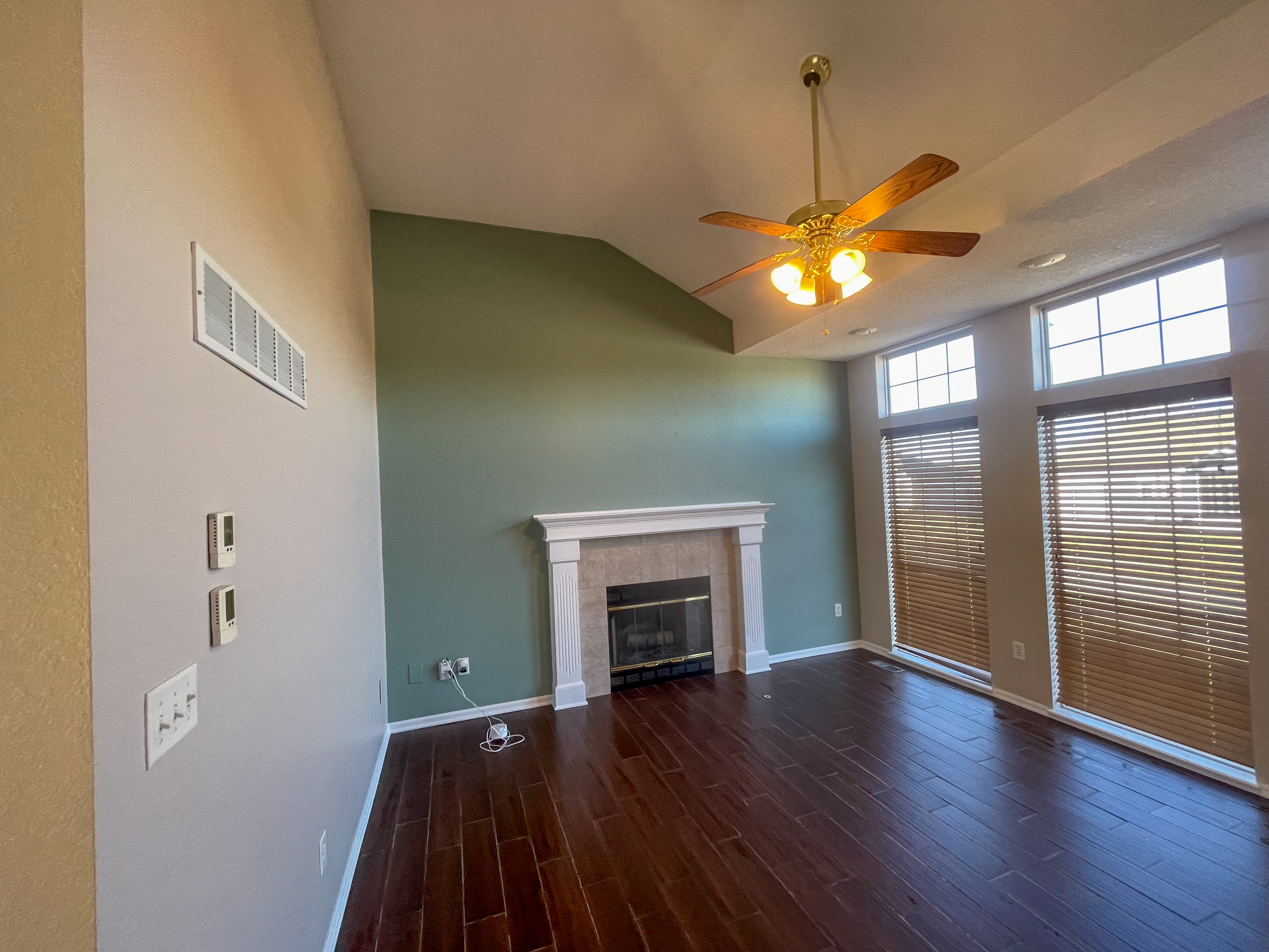 Beautiful sage green accent wall behind a white fireplace in a modern living room in Independence, MO by Red Letter Painting
